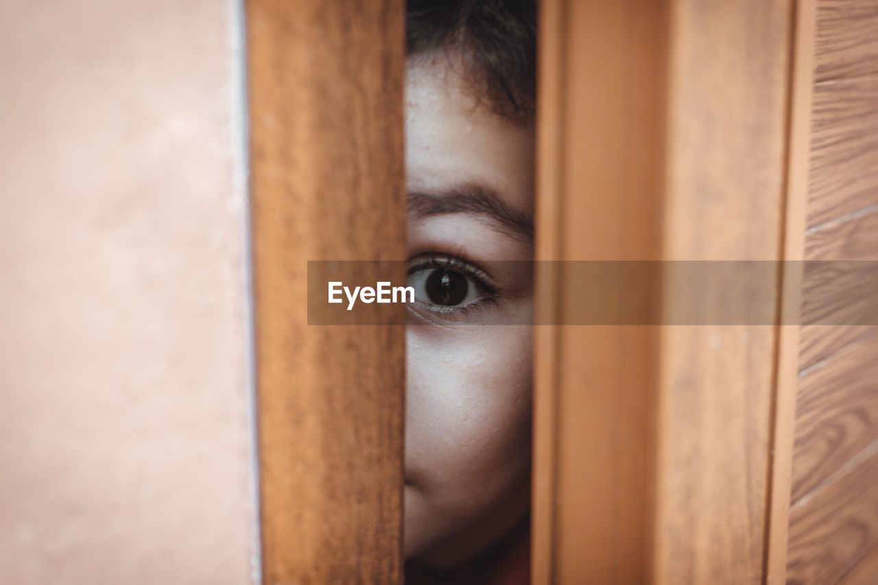 Close-up portrait of boy peeking from door