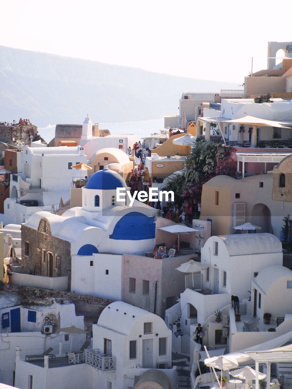 A hillside town in santorini, with traditional greek whitewashed buildings and blue roofs. 