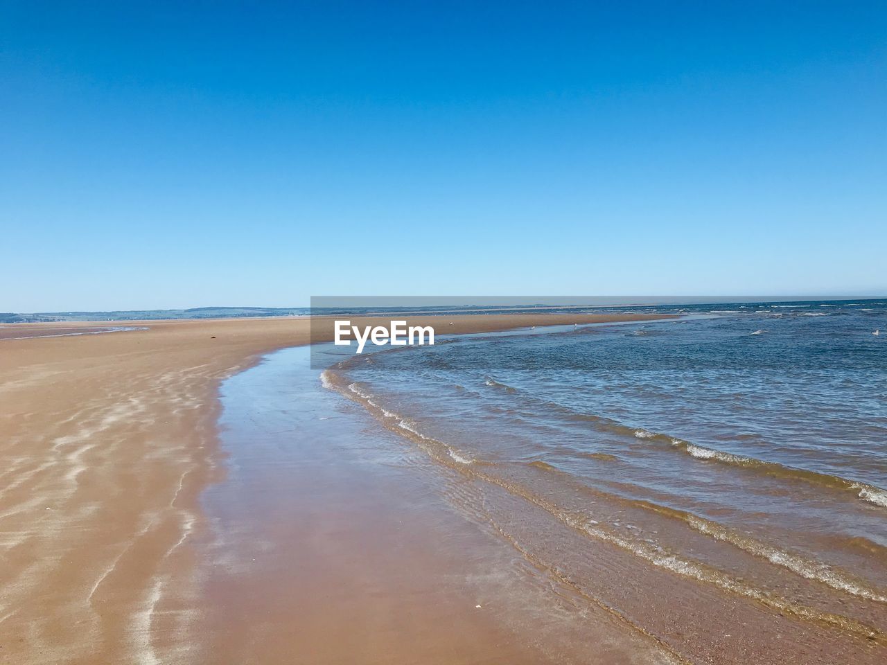 Scenic view of beach against clear blue sky