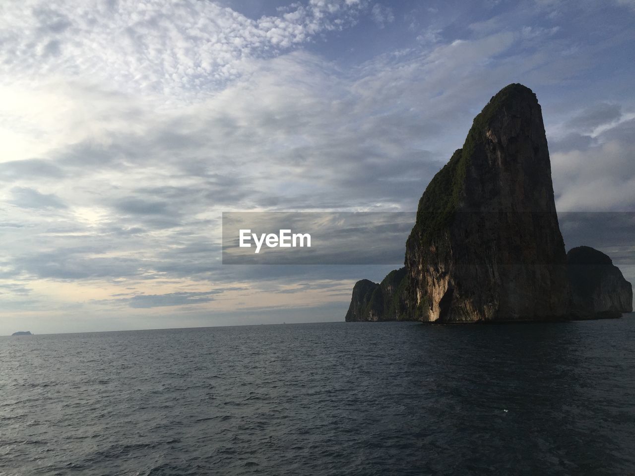 Rock formation in sea against sky during sunset