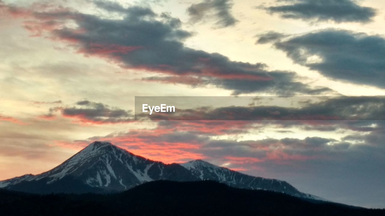 SCENIC VIEW OF MOUNTAINS AGAINST CLOUDY SKY DURING SUNSET