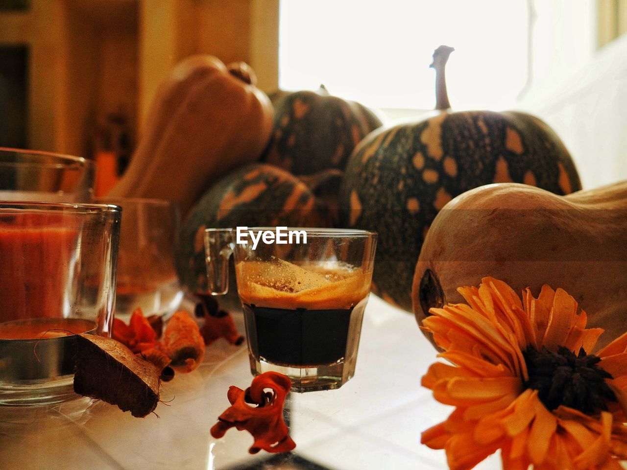 Coffee glass by pumpkins on table