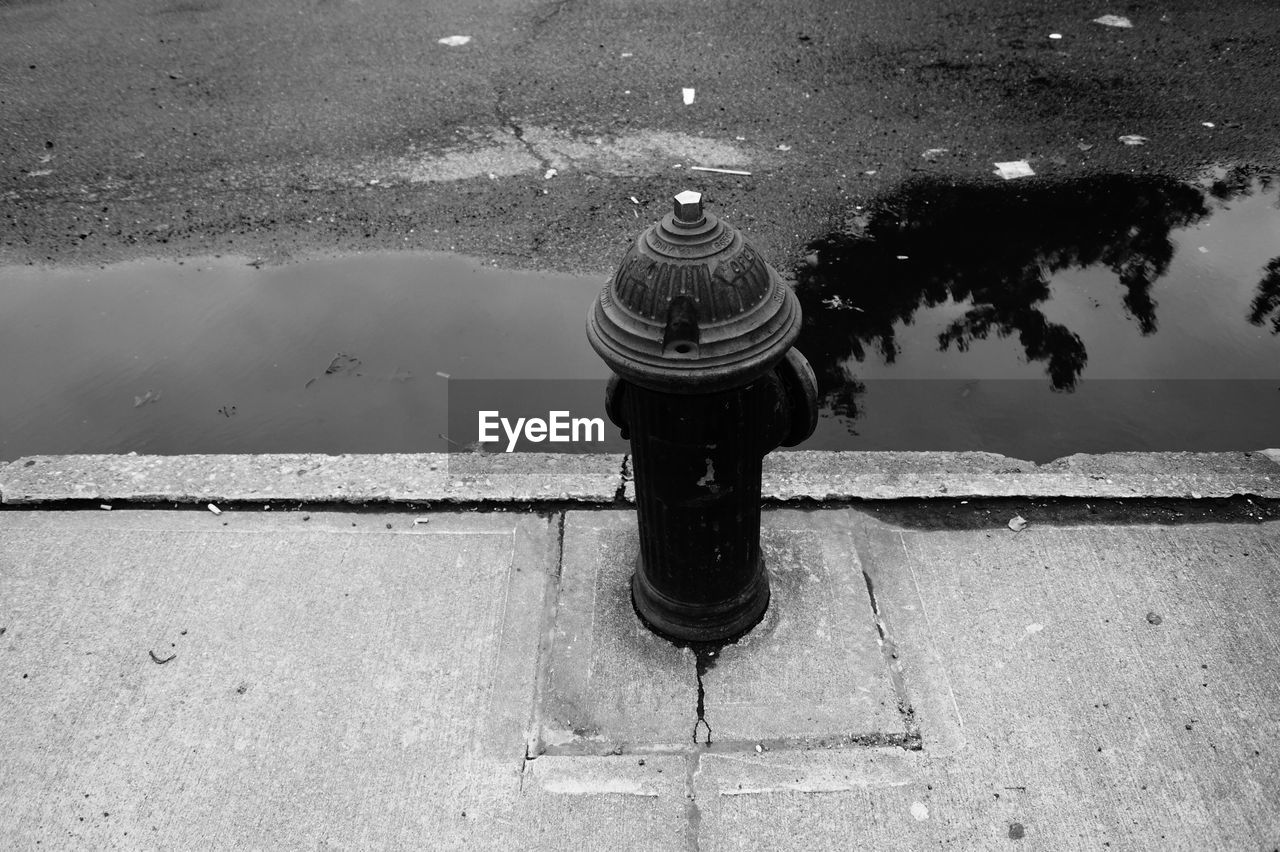 High angle view of fire hydrant on footpath by puddle