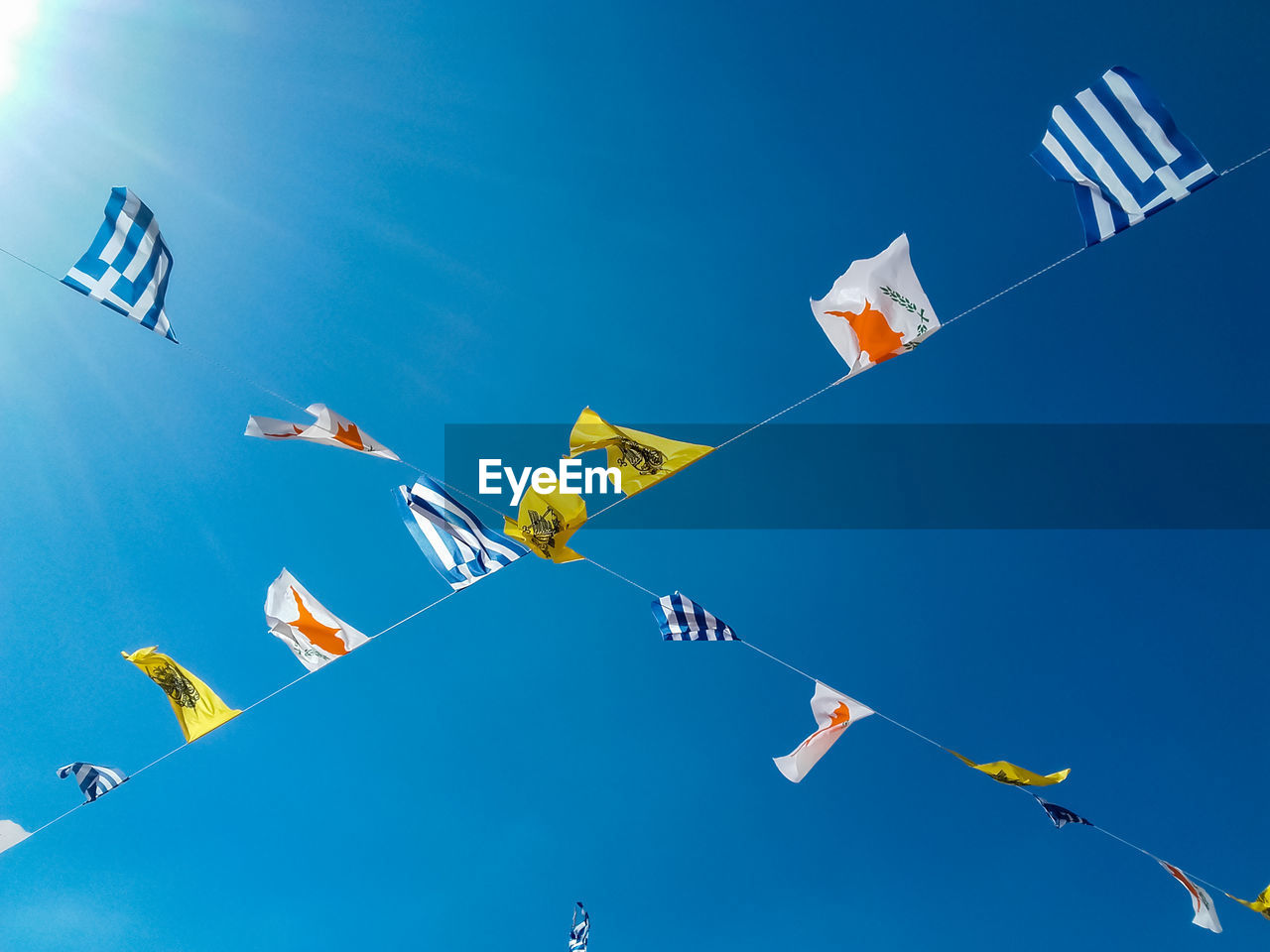 LOW ANGLE VIEW OF FLAGS AGAINST BLUE SKY