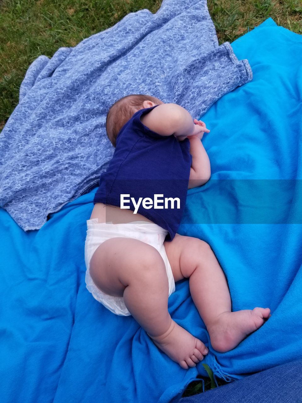 High angle view of baby boy lying on picnic blanket