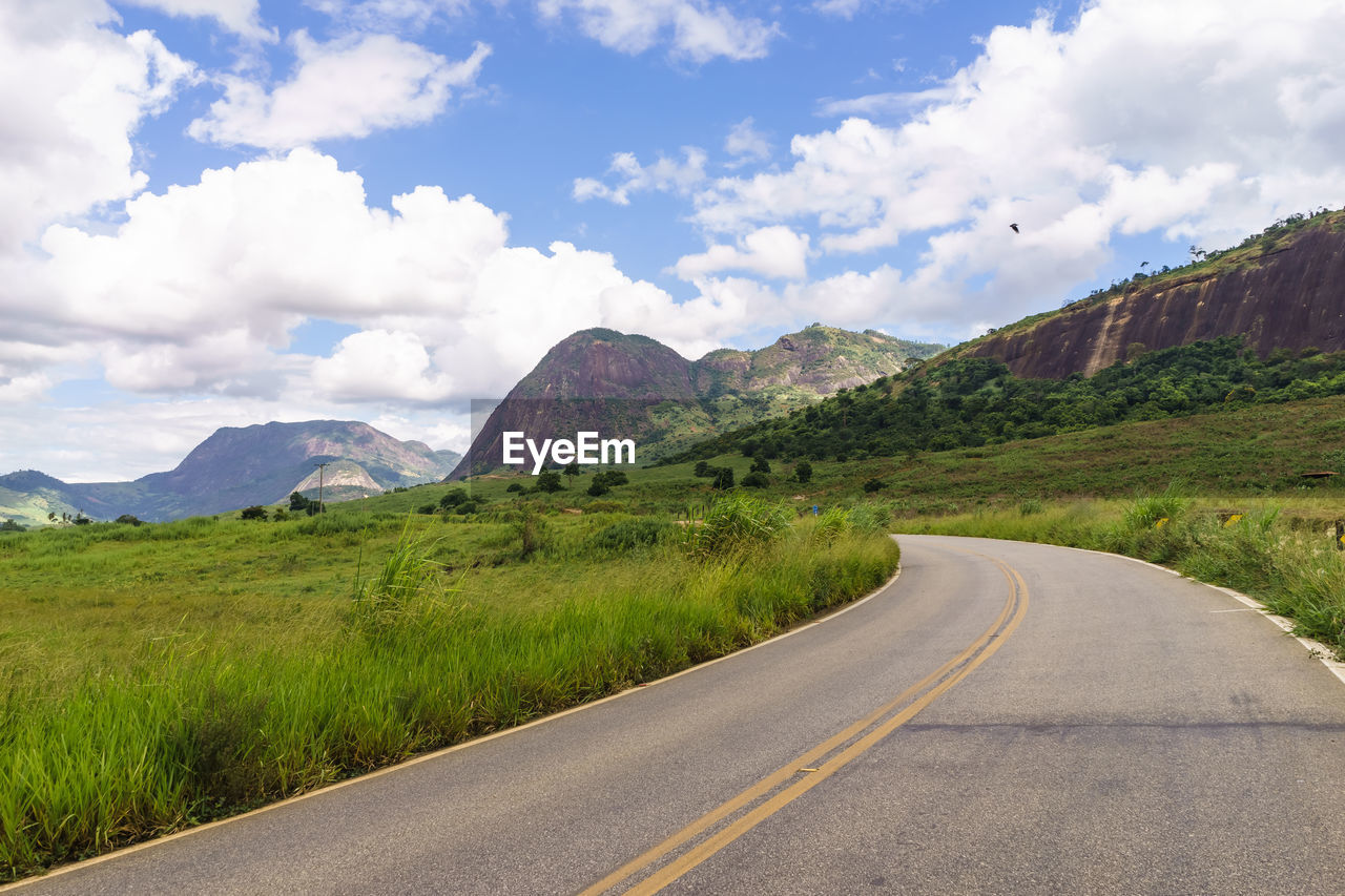 Road leading towards mountains against sky