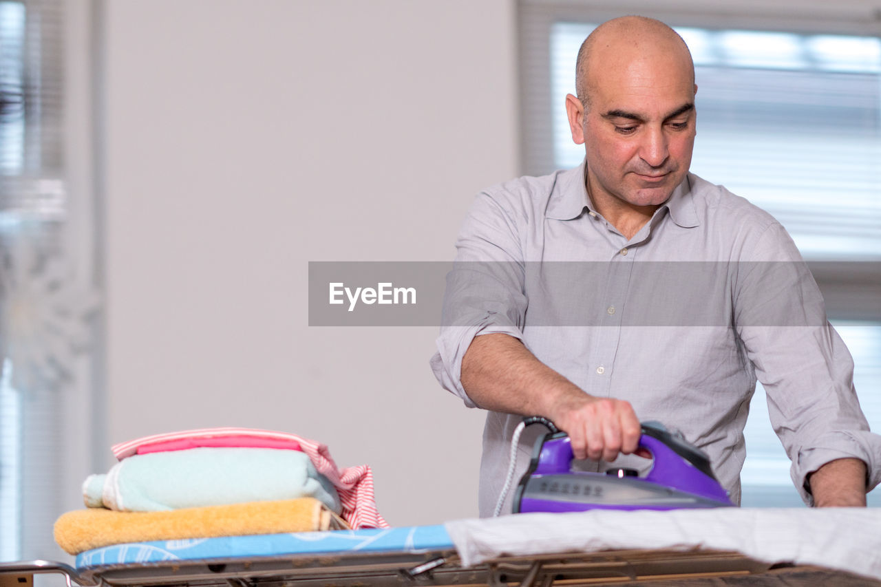 Man ironing clothes at home