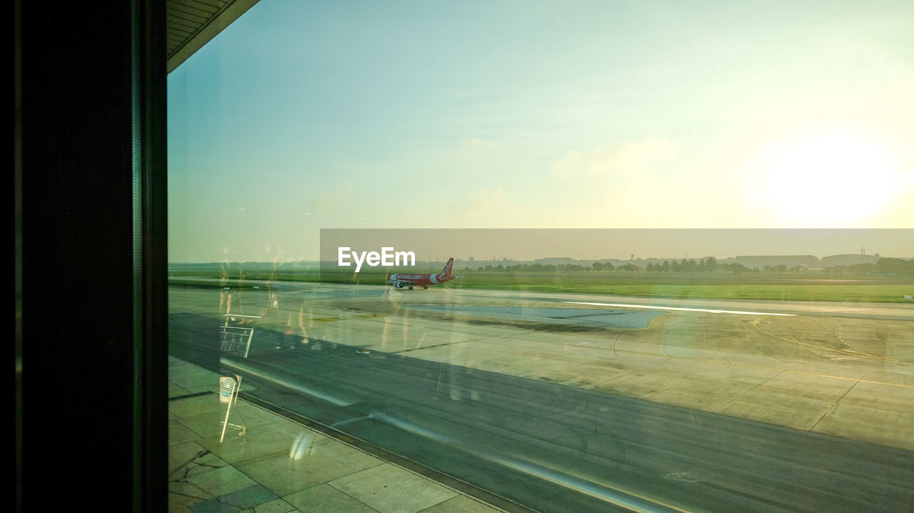 AIRPORT RUNWAY SEEN THROUGH GLASS WINDOW