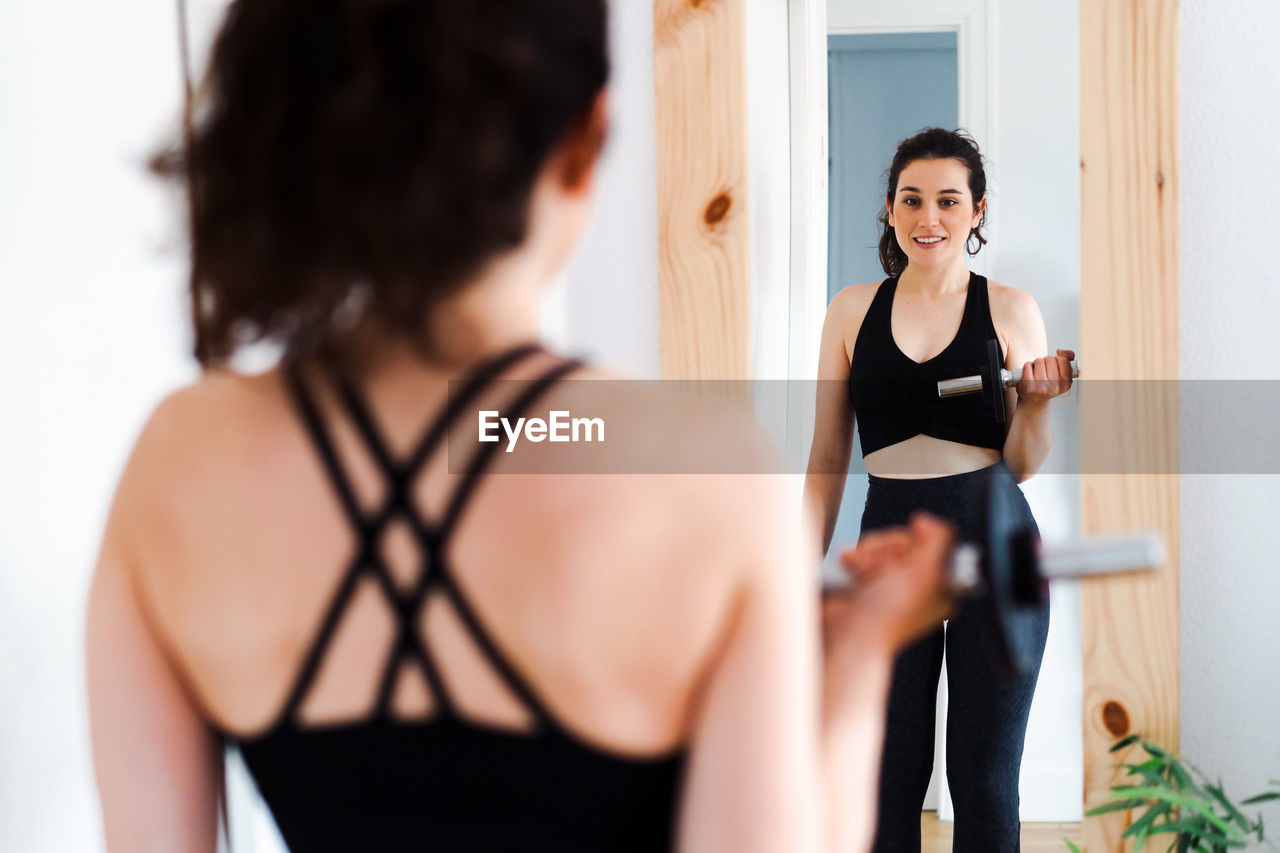 side view of young woman looking away while standing in gym