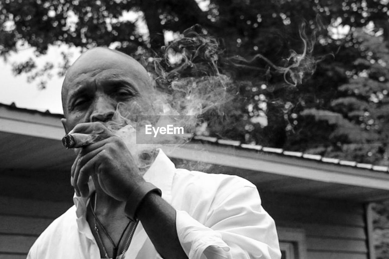 CLOSE-UP PORTRAIT OF MAN SMOKING CIGARETTE OUTDOORS