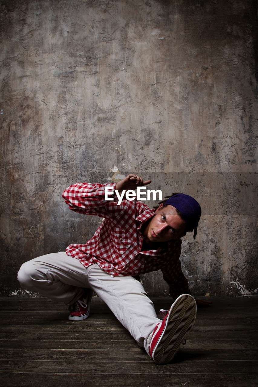 Full length of young man dancing against wall