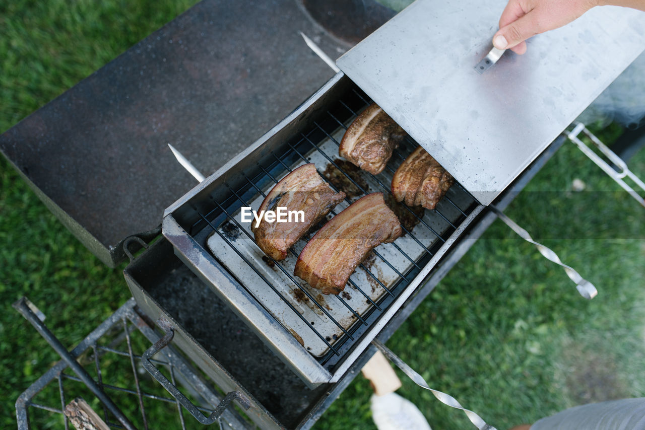 Bacon is smoked in a metal smokehouse in the open air