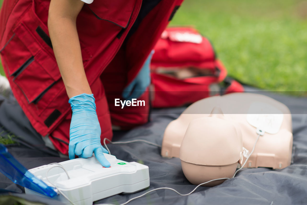 Midsection of paramedic practicing cpr on dummy