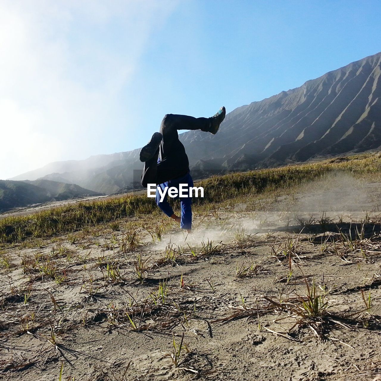 Full length of man doing handstand on field against sky