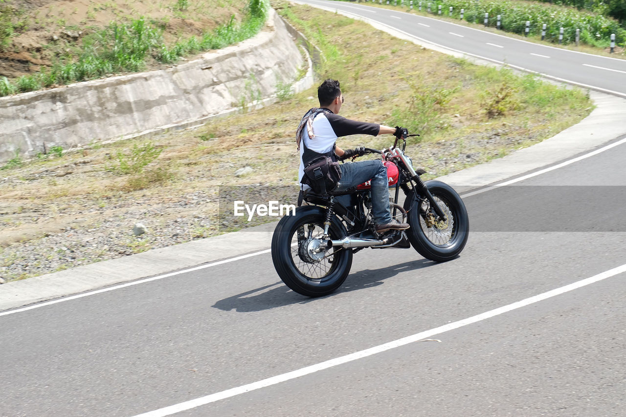 MAN RIDING MOTORCYCLE ON ROAD