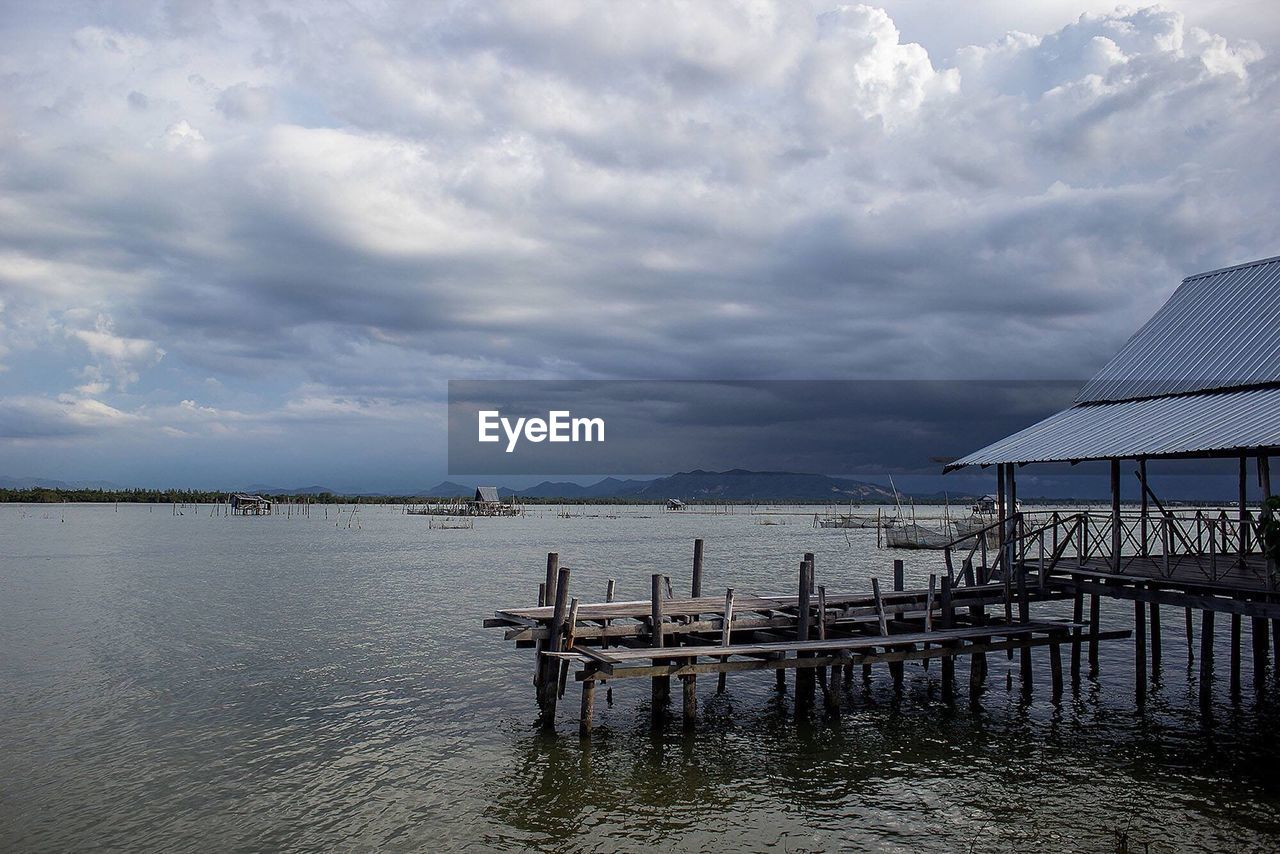 Pier on sea against cloudy sky