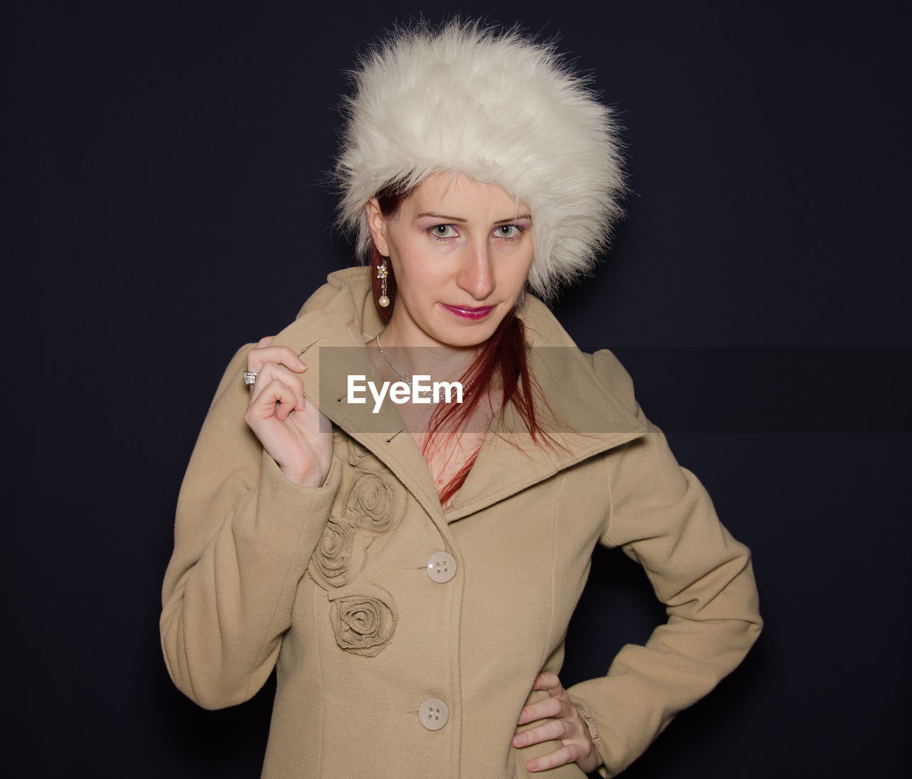 Portrait of woman wearing winter coat against black background