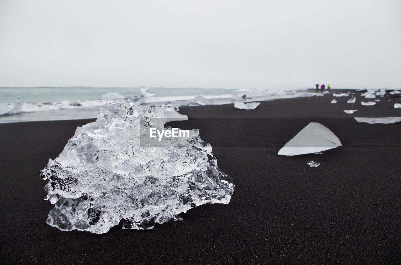 Close-up of ice at beach against clear sky