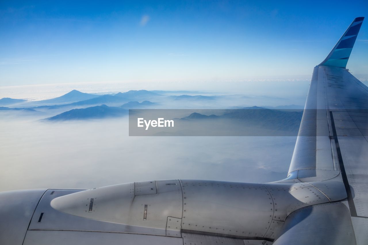 AIRPLANE FLYING ABOVE MOUNTAINS AGAINST SKY