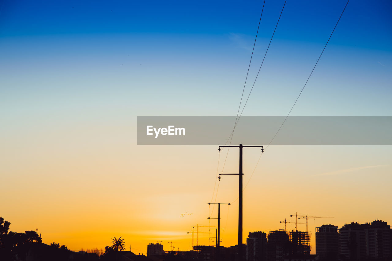 LOW ANGLE VIEW OF SILHOUETTE ELECTRICITY PYLONS AGAINST ROMANTIC SKY