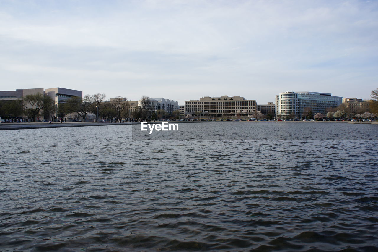 Sea by buildings against sky in city