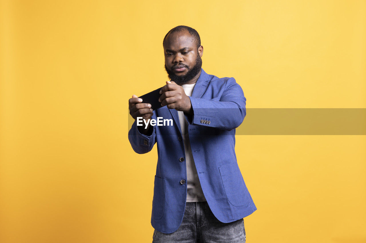 portrait of man standing against yellow background