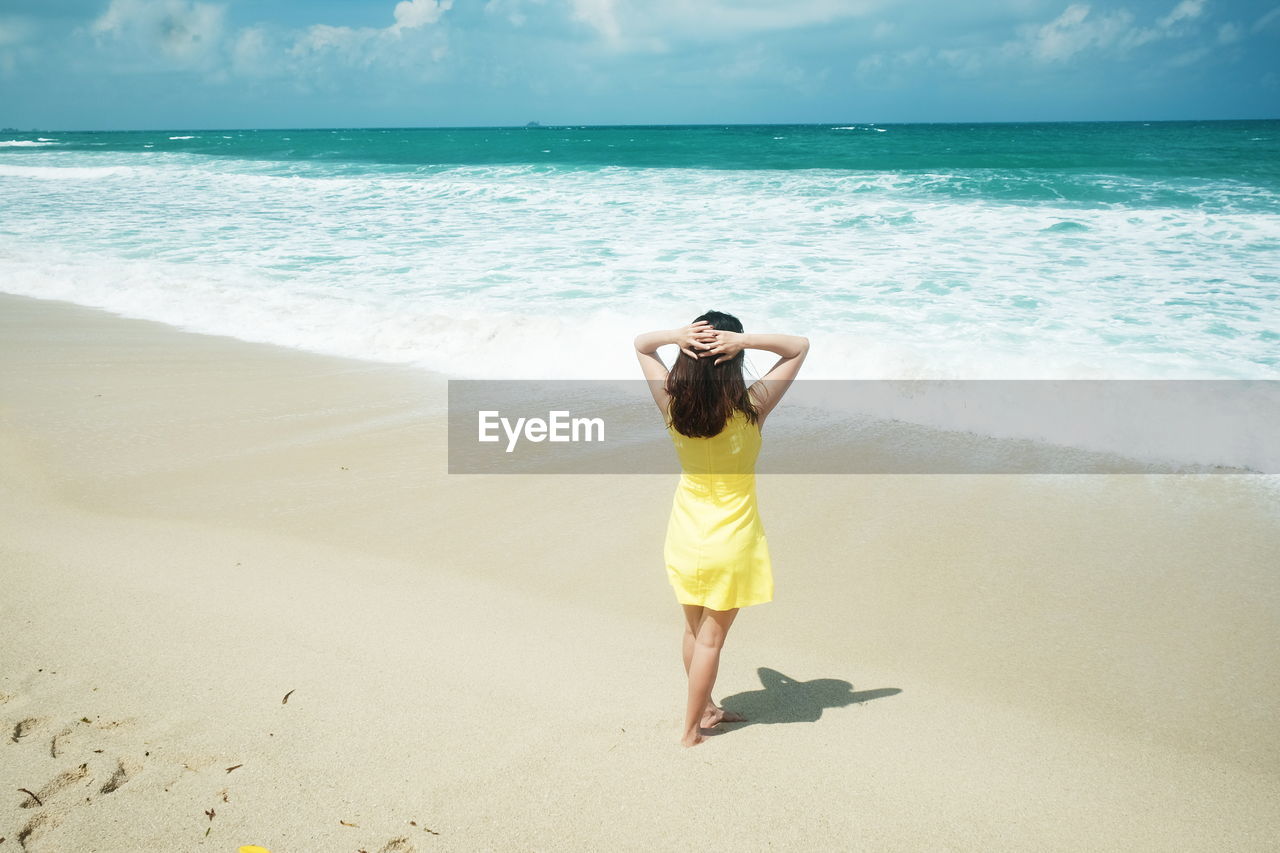 Rear view of young woman standing on beach