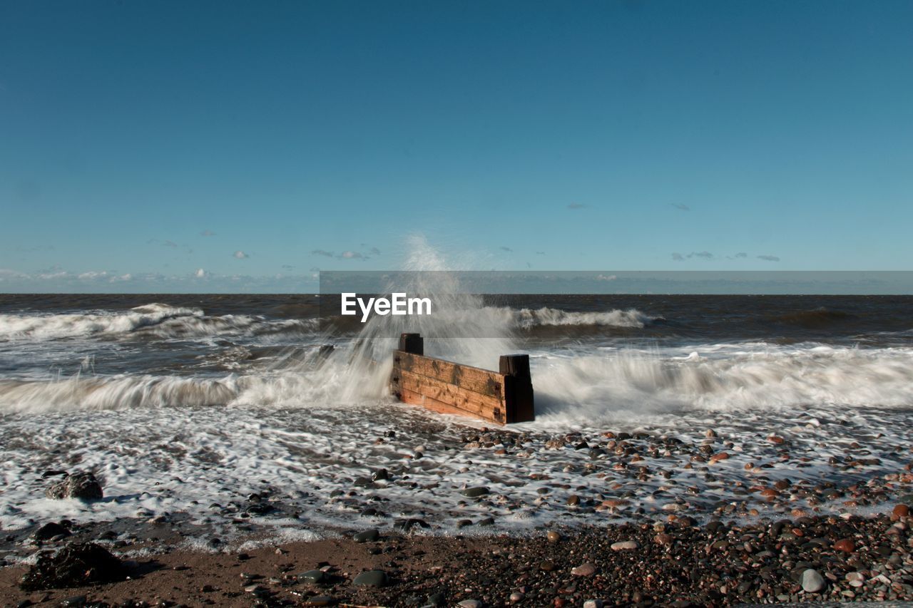 WAVE SPLASHING ON SHORE AGAINST CLEAR SKY