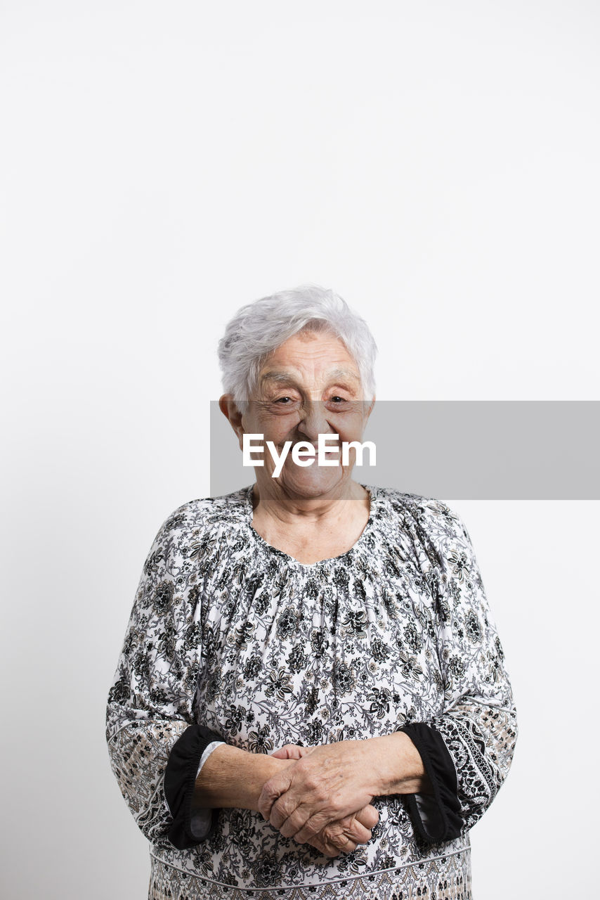 Portrait of happy senior woman in front of white background