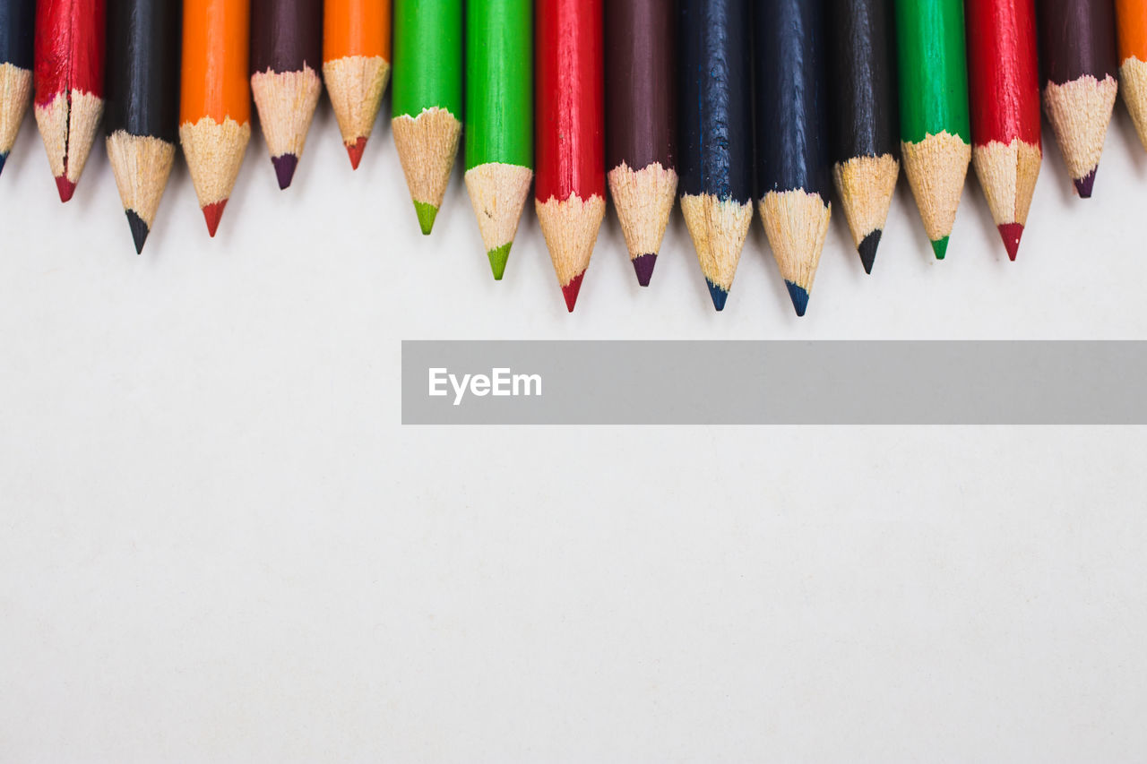 High angle view of colored pencils over white background