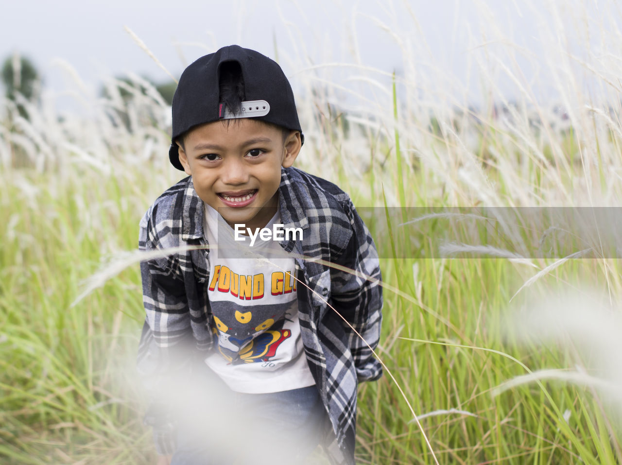 Portrait of smiling boy standing amidst plants on field