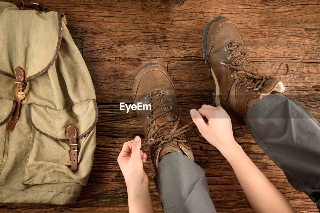 Low section of man wearing shoes by bag on floor