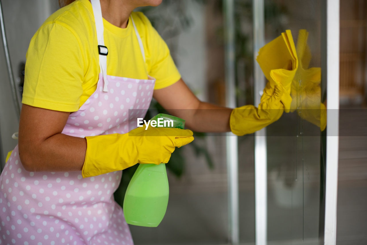 Professional cleaning of bathroom and toilet.  maid in an apron, rubber gloves and a yellow t-shirt 