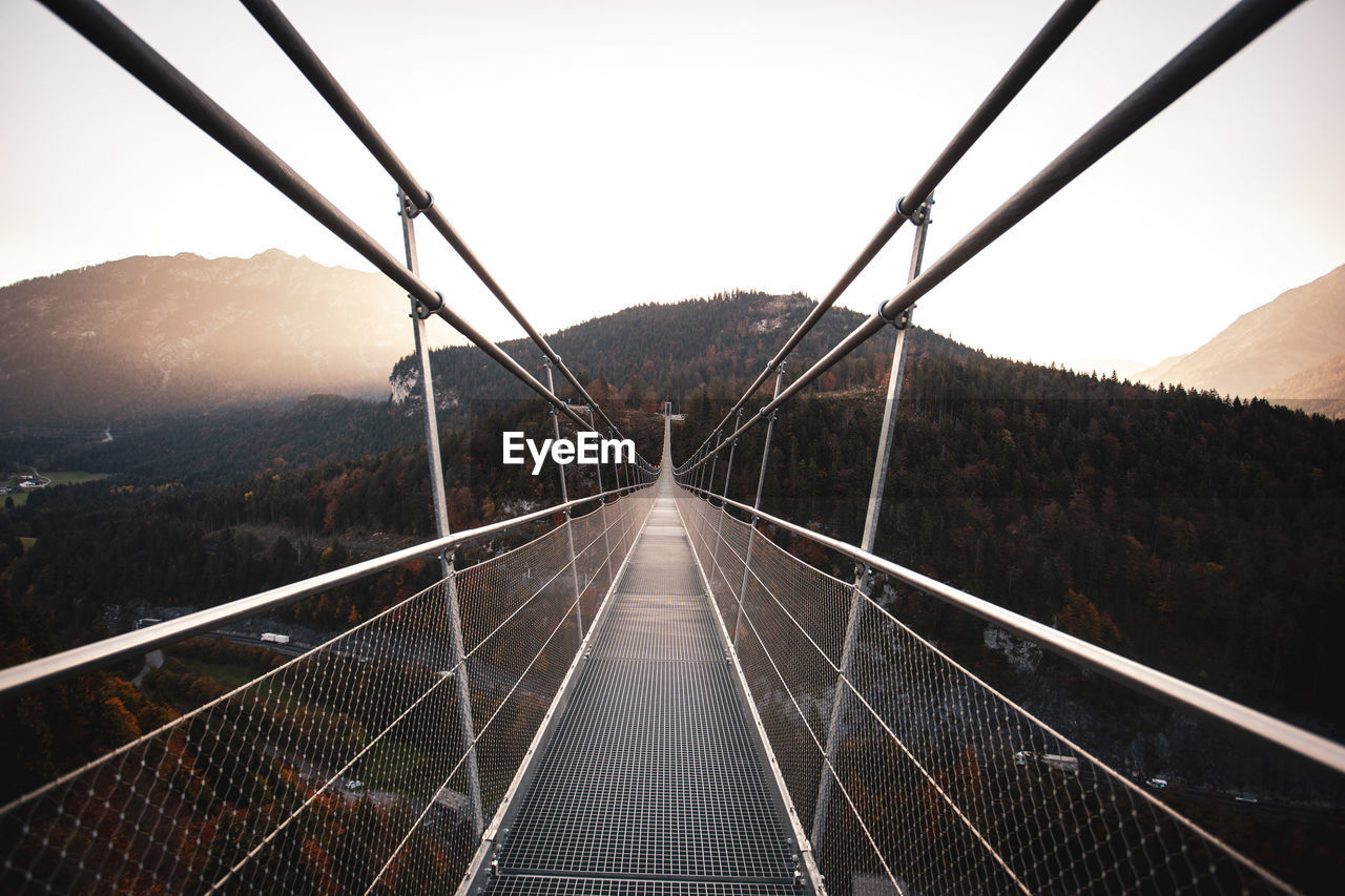 Long empty footbridge against clear sky during sunrise