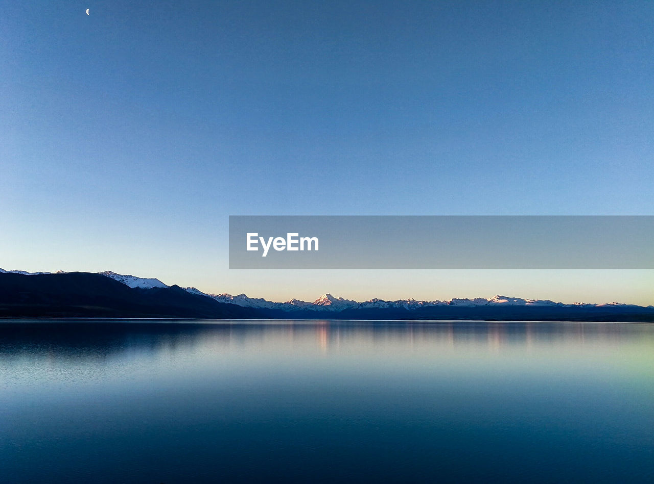 Scenic view of lake against clear blue sky