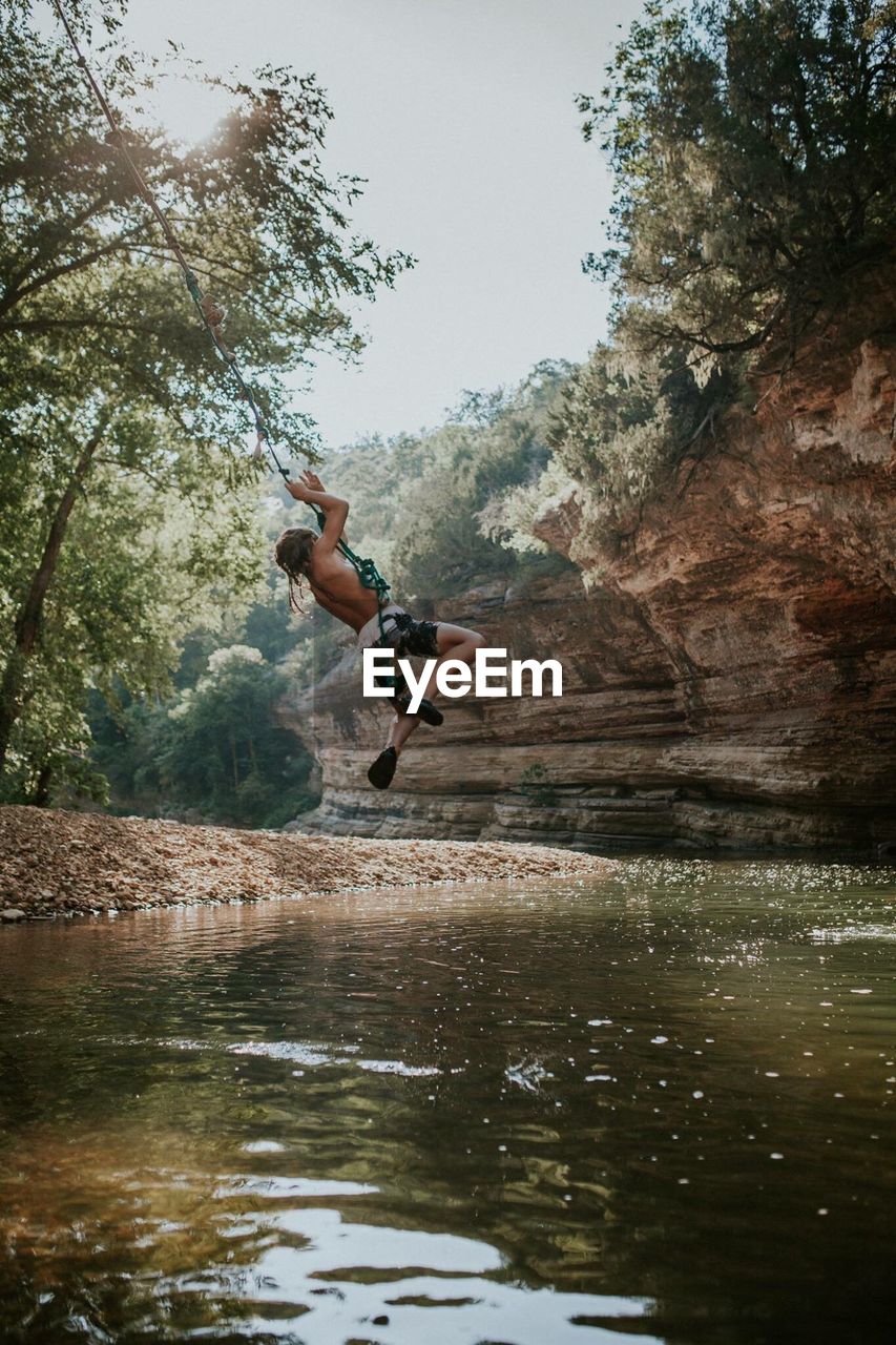 MAN JUMPING ON ROCK IN LAKE