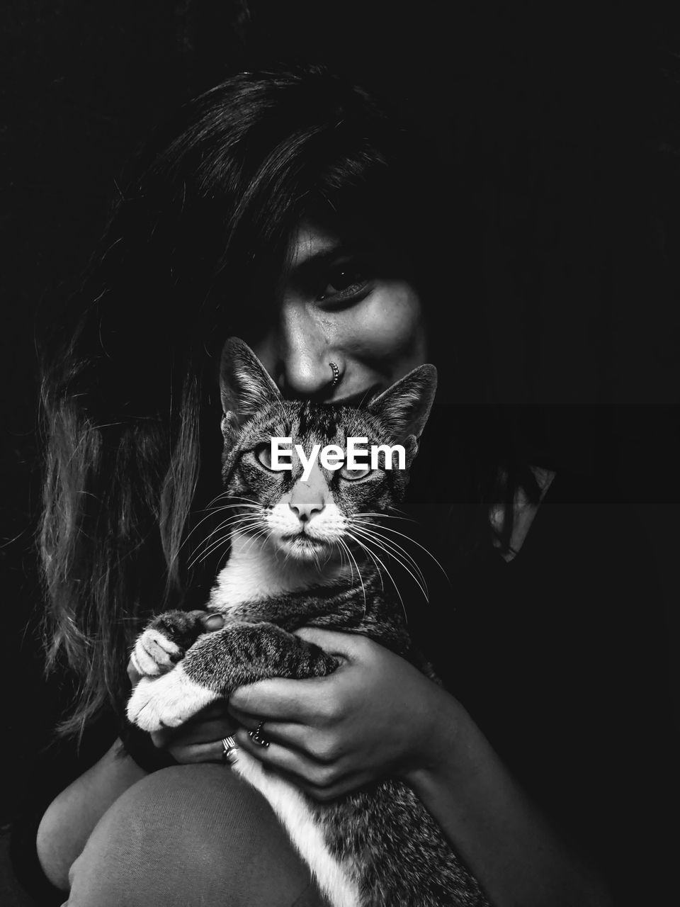 Portrait of woman with cat against black background