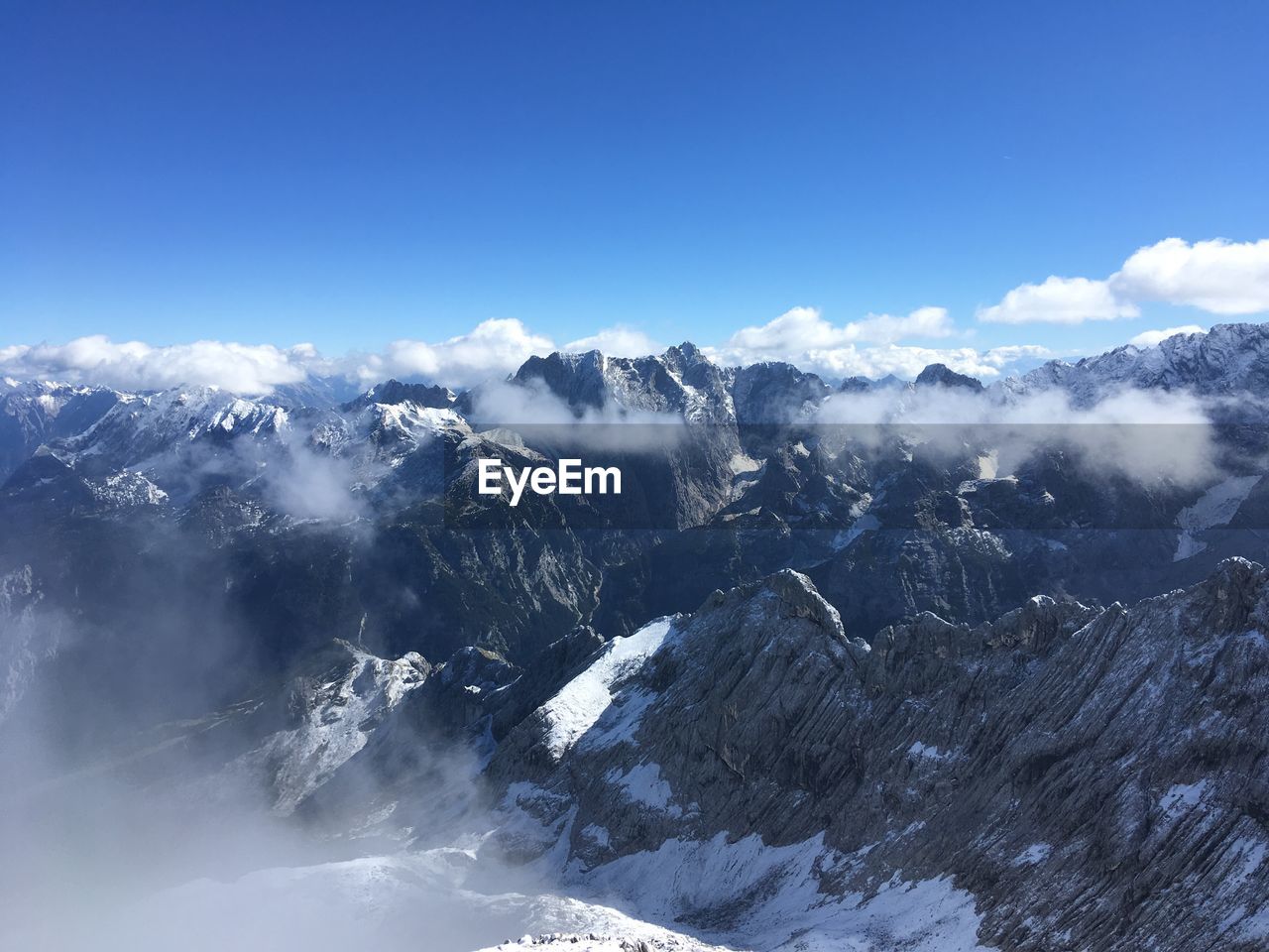 Aerial view of snowcapped mountains against blue sky