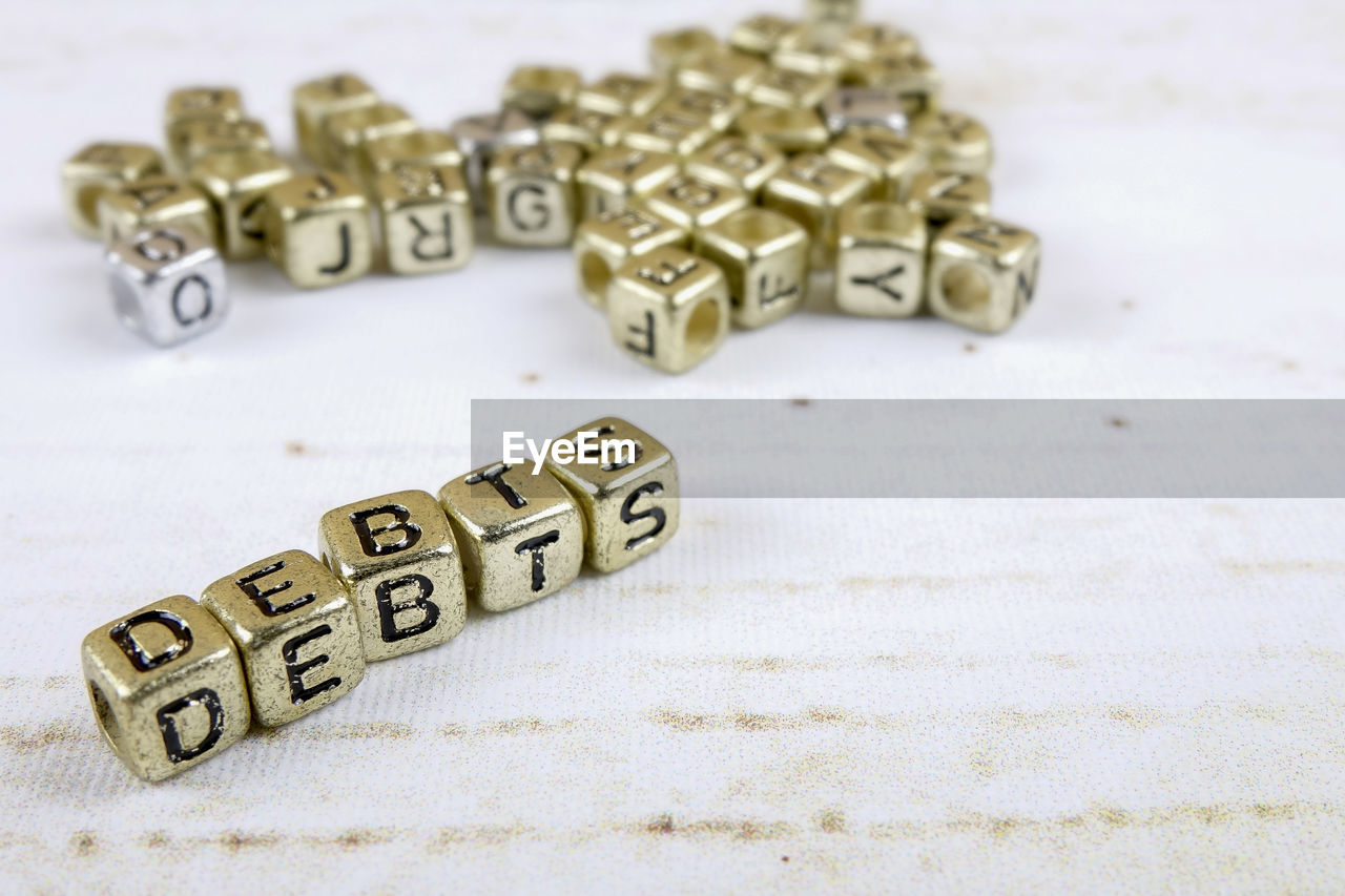 Close-up of debt text made with golden toy blocks on table