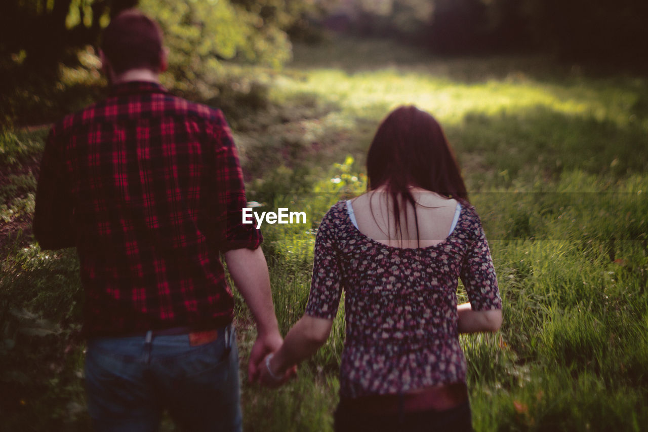 Rear view of couple walking on field