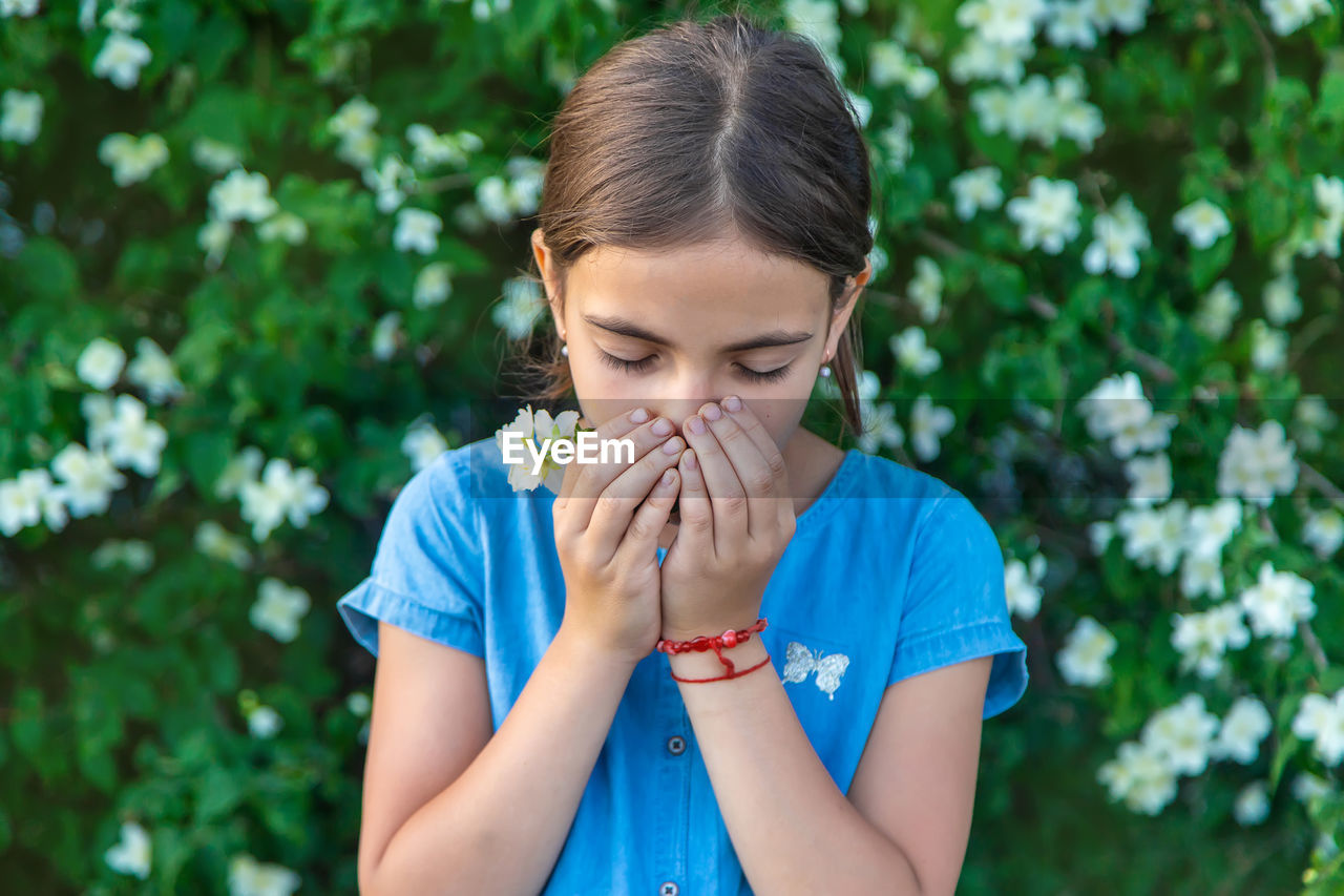 Girl sneezing while smelling flower