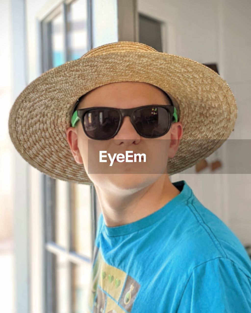 Portrait of teen boy wearing straw hat and sunglasses