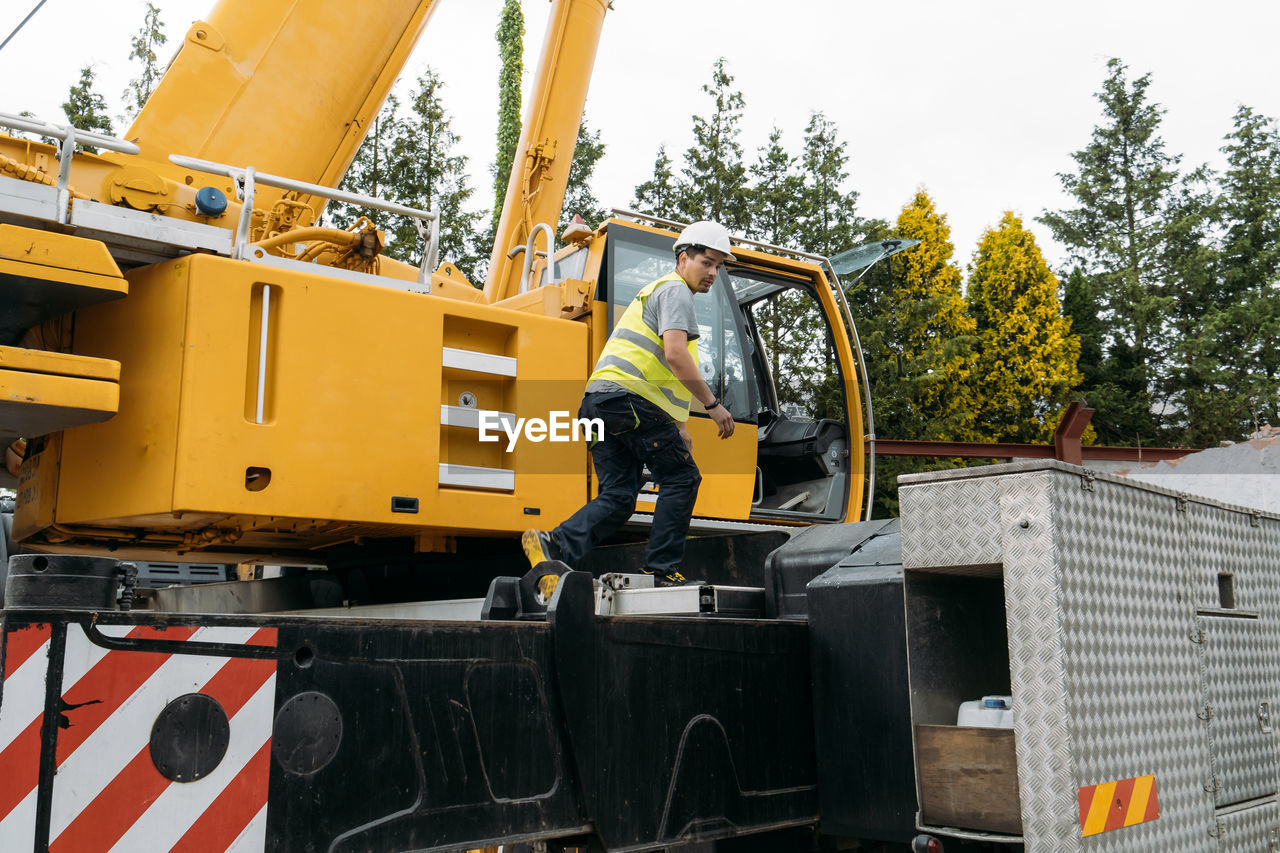 Operator climbing on construction crane lifting heavy freight. modern mobile transportation