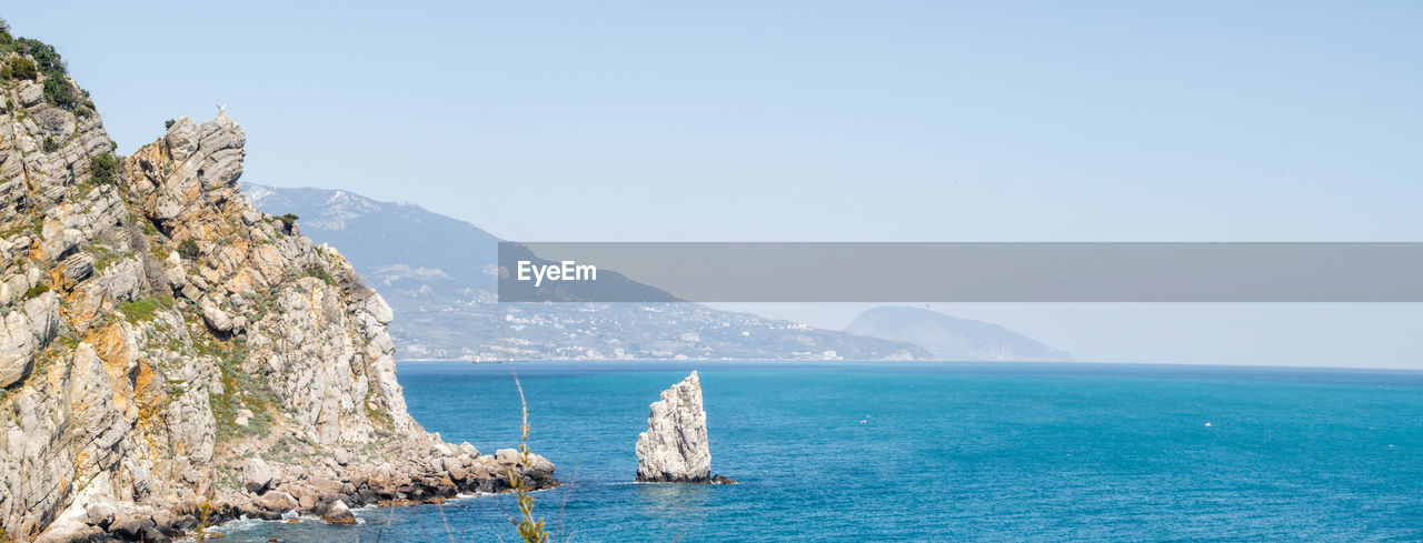 Scenic view of sea and mountains against clear sky