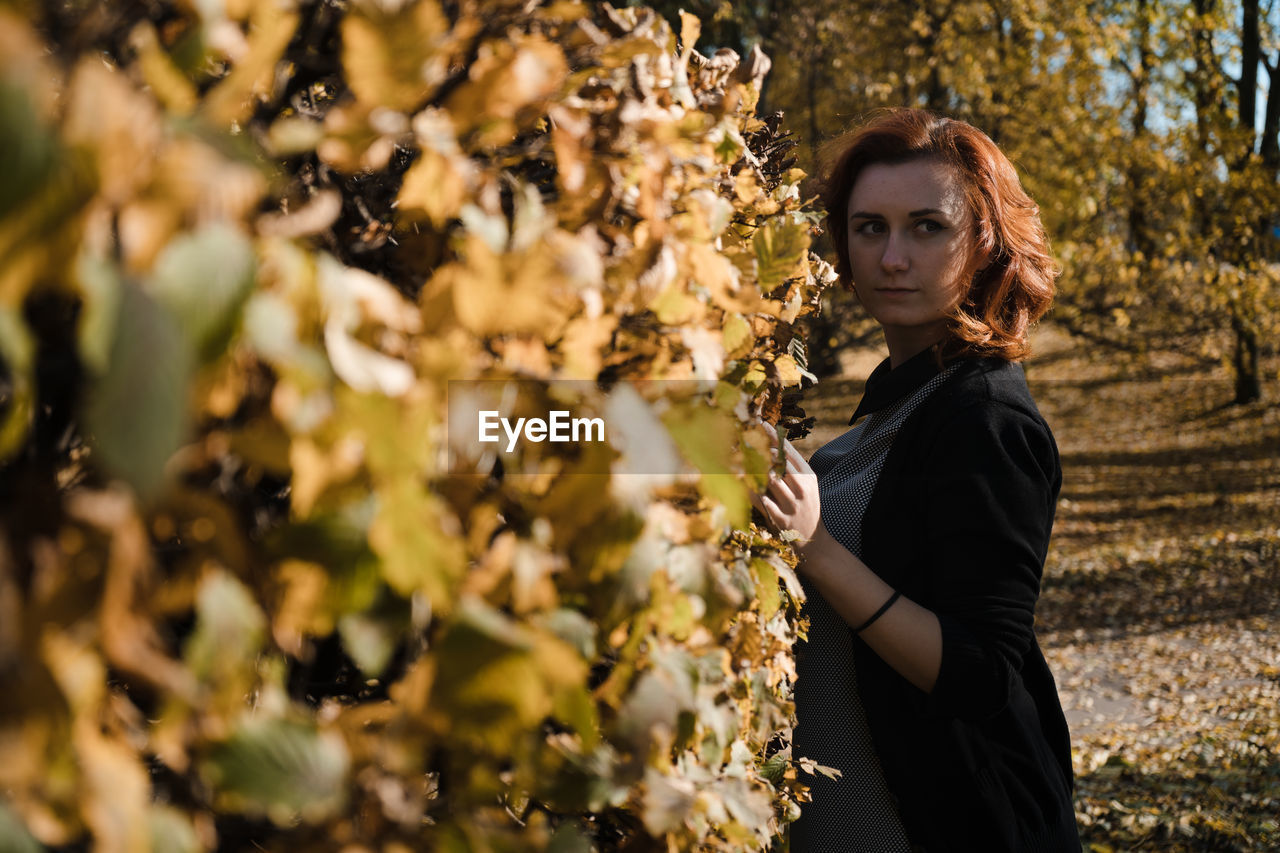 Side view of woman standing by plants during autumn