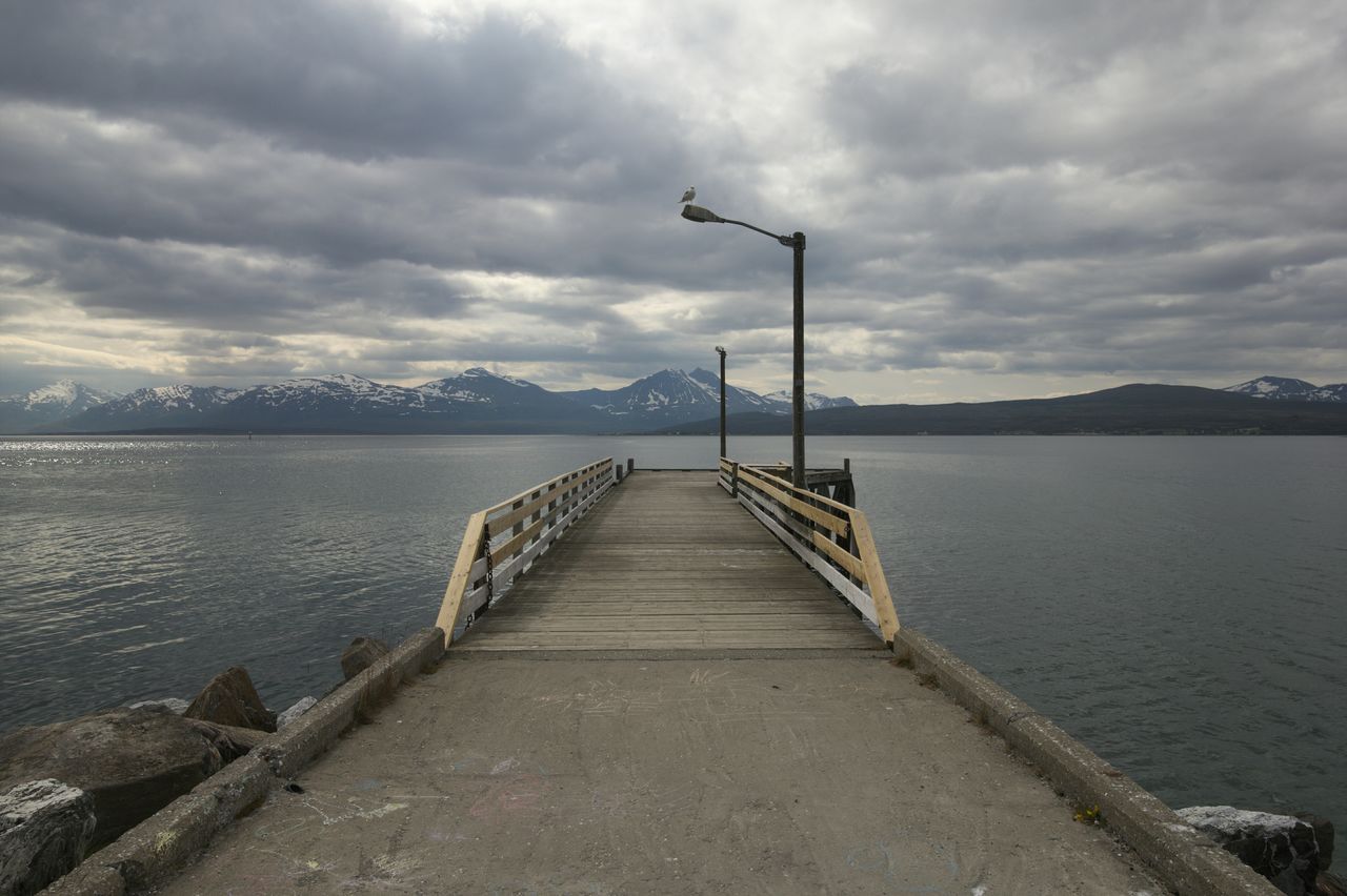 Pier over sea against cloudy sky