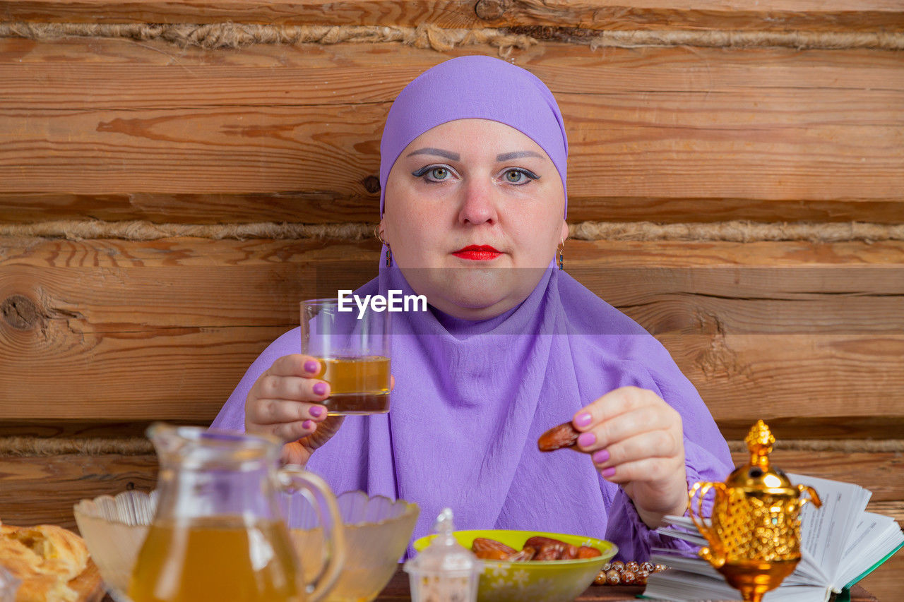 portrait of young woman drinking glass on table at home