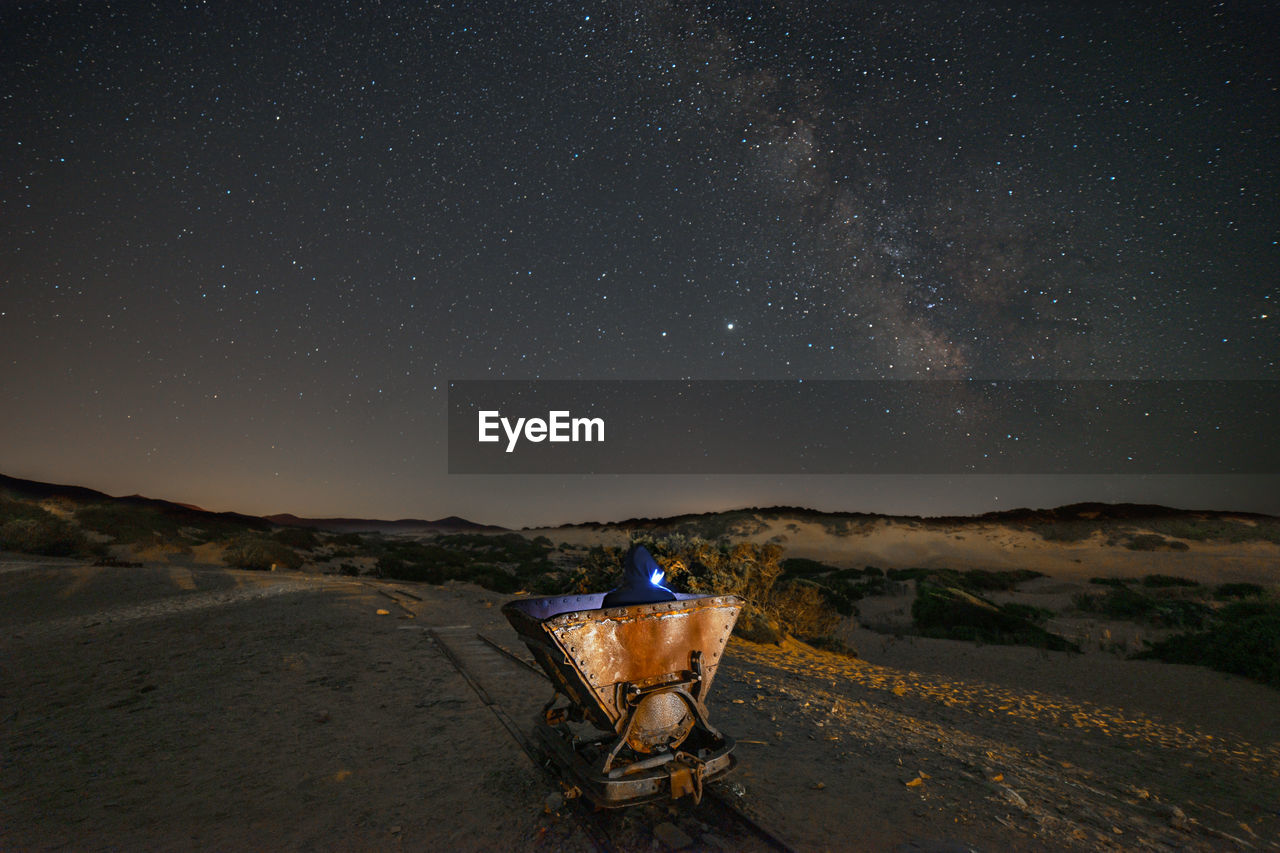 Old rusty minerali carriera on land against star field at night