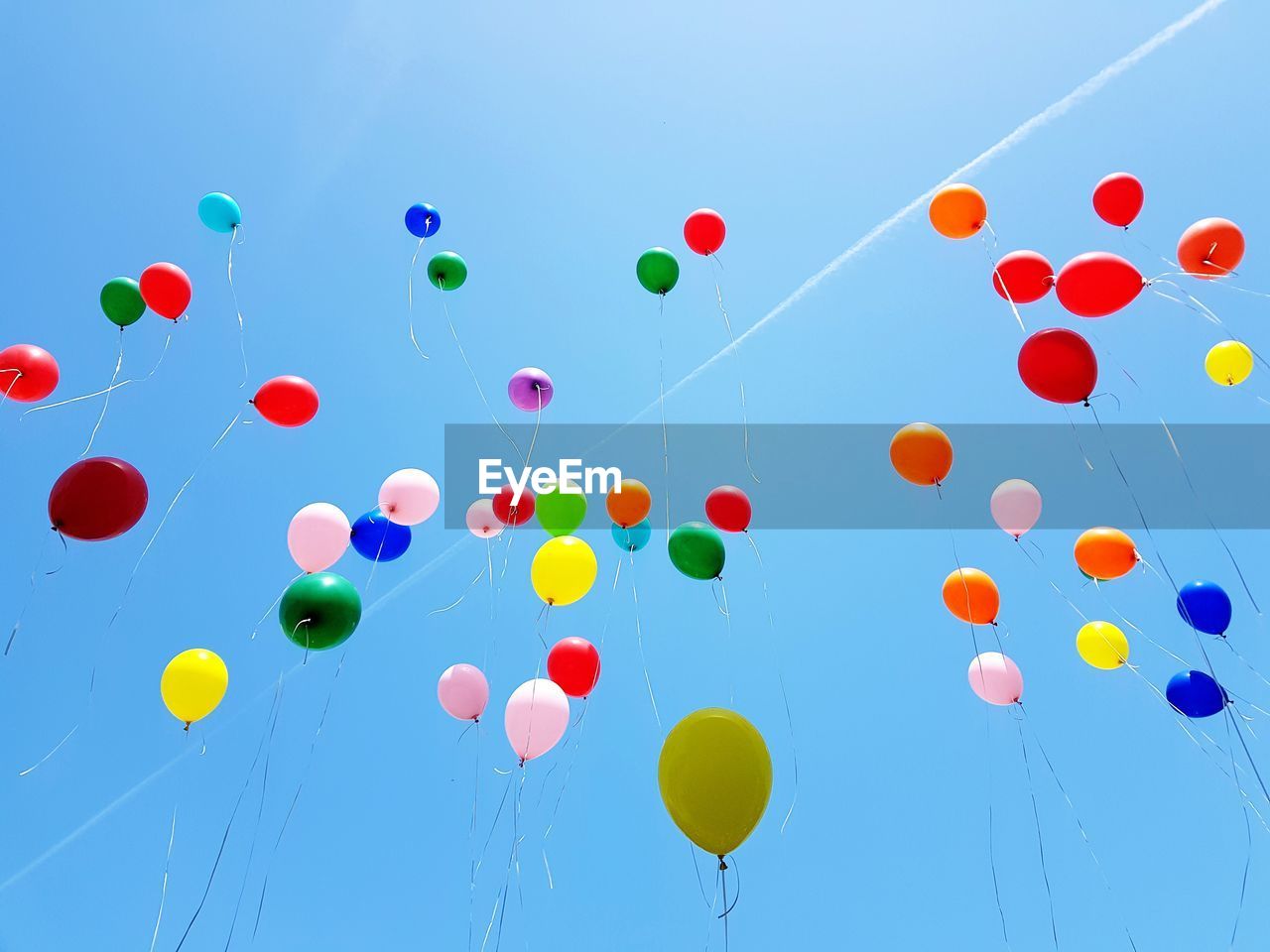 Low angle view of balloons flying against blue sky