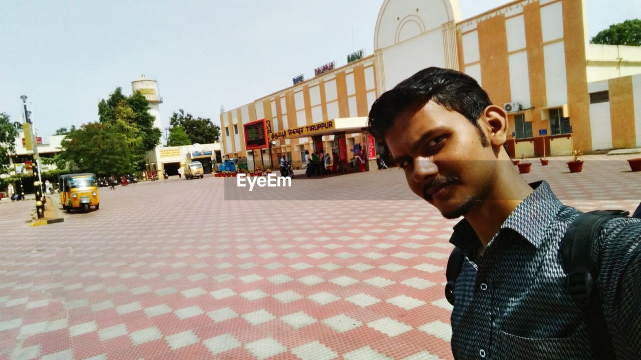 MIDSECTION OF MAN IN CITY AGAINST SKY IN BACKGROUND